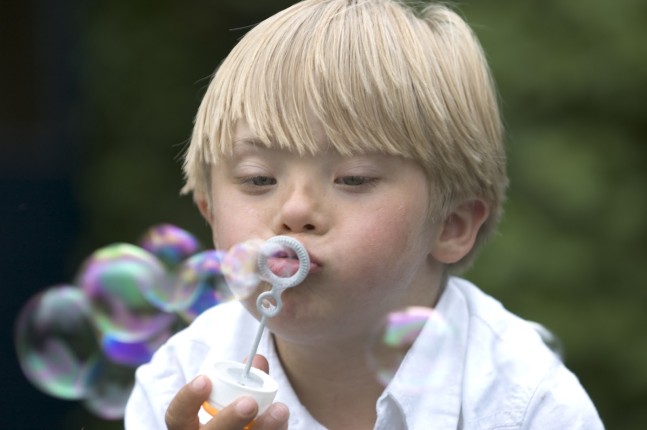 9439332-Boy-with-Down-Syndrome-blows-bubbles_MED